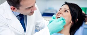 Dentist with mouth mirror checking patient mouth