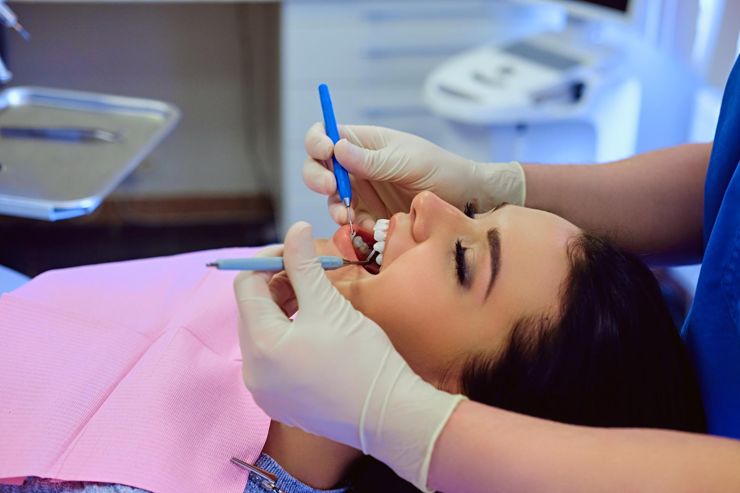 Close-up of a dentist examining a female patient’s mouth during wisdom teeth removal.
