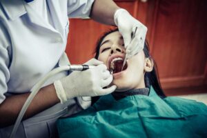 Woman receiving wisdom teeth removal treatment from a dental professional in clinic