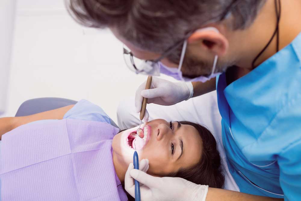 Dental professional performing wisdom teeth removal treatment for a woman in a clinical setting